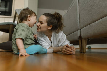 Mother playing with baby girl on floor at home - IEF00409