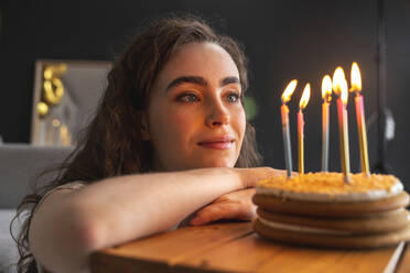 Junge Frau betrachtet Torte bei der Geburtstagsfeier zu Hause - VPIF08036