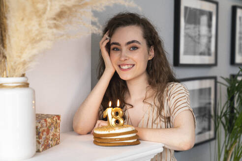 Lächelnde junge Frau mit Geburtstagstorte zu Hause - VPIF08037