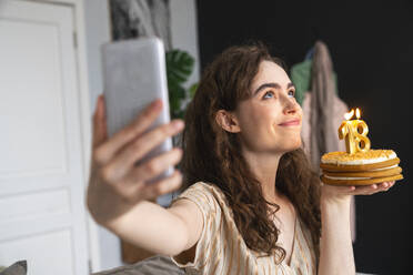 Fröhliche Dame, die einen Moment mit ihrer Geburtstagstorte durch ein lustiges Selfie festhält - VPIF08044