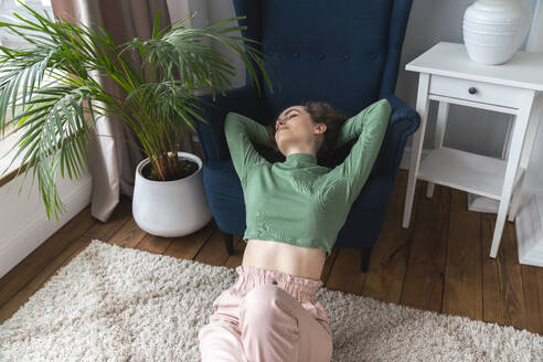 Young woman leaning on armchair at home - VPIF08062