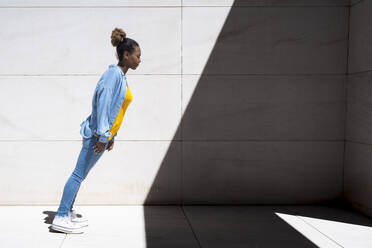 Young woman leaning in front of wall at sunny day - JCZF01260