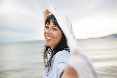 Happy mature woman enjoying with scarf at beach - JOSEF19199