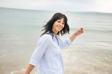 Lächelnde Frau mit langen Haaren genießt am Strand - JOSEF19214