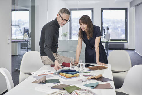 Kreativer Geschäftsmann und Geschäftsfrau diskutieren im Büro über Farbmuster - RORF03563