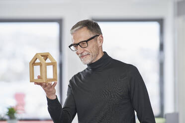 Senior architect looking at model house in office - RORF03586