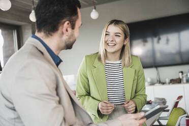 Smiling businesswoman discussing with coworker in office - UUF28688