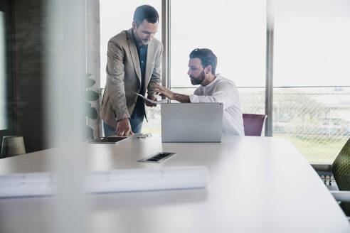 Businessman explaining document to coworker at table - UUF28695