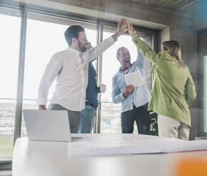 Business colleagues giving high-five in meeting room - UUF28718