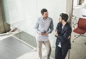 Geschäftskollegen diskutieren an die Glastür gelehnt im Büro - UUF28725