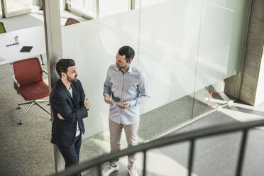 Business coworkers discussing by glass door in office - UUF28727