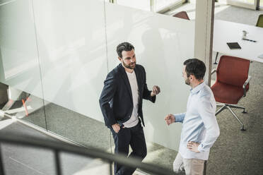 Business coworkers discussing leaning on glass door in office - UUF28728