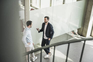 Geschäftskollegen diskutieren an die Glastür gelehnt im Büro - UUF28729