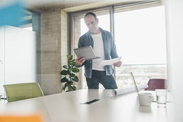 Geschäftsmann mit Blick auf einen Tablet-PC im Büro - UUF28735