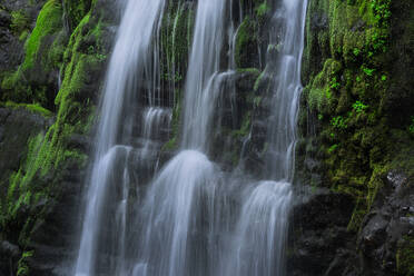 Malerischer Blick auf einen Wasserfall, der im Sommer von einer mit Moos bewachsenen Felswand herabstürzt - ADSF44199