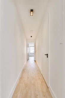 Innenarchitektur des leeren Flurs mit weißen Wänden und Holzboden gegen Tür und Lampe in einem modernen Wohnhaus - ADSF44239