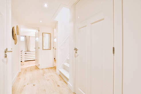 Minimalistischer Korridor in der Nähe der Treppe, dekoriert mit weißen Wänden und Türen in einer modernen Wohnung - ADSF44249