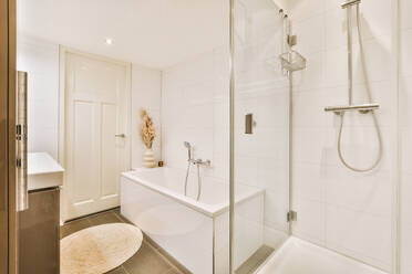 Interior design of hygiene bathroom with bathtub washbasin and glass shower cabin provided with hanging taps to supply water in illuminated lights of modern apartment with white walls - ADSF44252