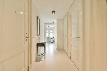 Inneneinrichtung eines langen Flurs mit weißen Türen und Schminktisch mit Spiegel in einer modernen Wohnung - ADSF44254