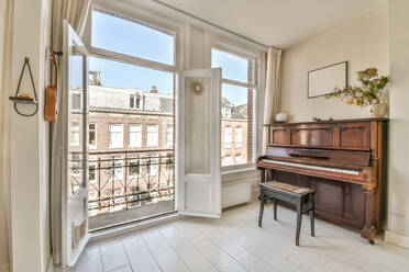 Creative interior design of room with piano and decorative elements near opened door in light apartment - ADSF44284