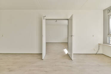 Inneneinrichtung eines hellen geräumigen Zimmers mit weißen Wänden und geöffneter Tür in einer modernen Wohnung - ADSF44300
