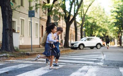 Fröhliche kleine Mädchen überqueren Straße im Freien in der Stadt, Coronavirus Konzept. - HPIF15430