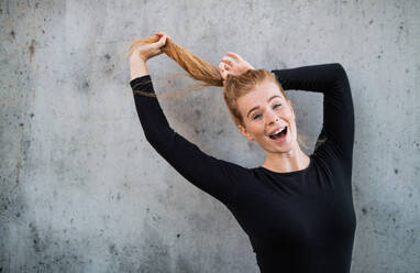 Front view portrait of cheerful young woman with red hair standing against gray background, looking at camera. - HPIF15443