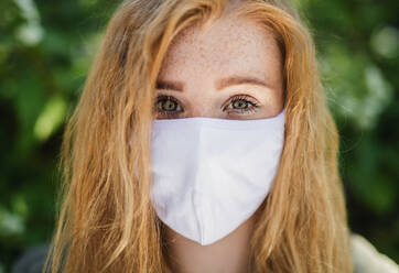 Nahaufnahme einer jungen Frau mit roten Haaren, die in der Stadt im Freien steht, Konzept des Coronavirus. - HPIF15461