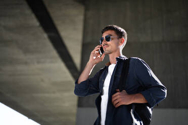 Porträt eines jungen attraktiven Mannes mit Kopfhörern und Smartphone beim Spaziergang in der Stadt. - HPIF15478