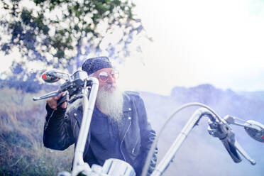 Ein älterer Mann mit Motorrad und Sonnenbrille auf dem Lande. - HPIF15490