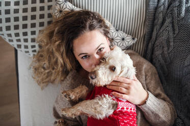 Draufsicht auf eine junge Frau, die sich zu Hause auf dem Sofa mit ihrem Hund entspannt. - HPIF15521