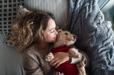 Top view of happy young woman relaxing indoors on sofa at home with pet dog. - HPIF15522