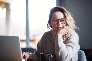 Porträt einer jungen Frau mit Laptop und Kaffee, die sich zu Hause entspannt. - HPIF15527
