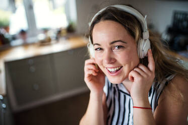 Happy young woman with headphones relaxing indoors at home, listening to music. - HPIF15533