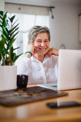 Portrait of senior woman with laptop and smartphone working in home office. - HPIF15535