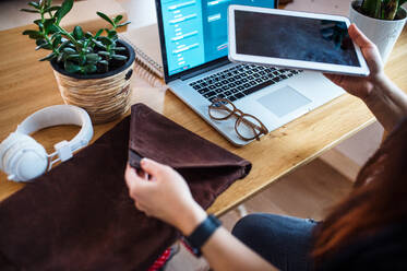 Mittelteil einer älteren Frau mit Tablet und Laptop bei der Arbeit im Heimbüro. - HPIF15541