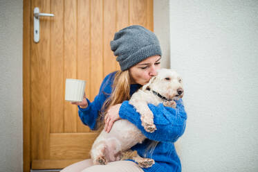 Ältere Frau entspannt sich im Freien vor der Haustür mit Kaffee und Hund. Raum kopieren. - HPIF15567