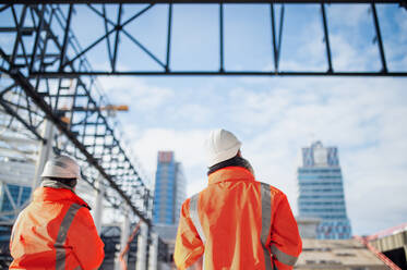 Rückansicht von Ingenieuren oder Arbeitern, die im Freien auf einer Baustelle stehen. - HPIF15593