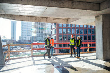 Eine Gruppe von Ingenieuren steht auf einer Baustelle und unterhält sich. - HPIF15594