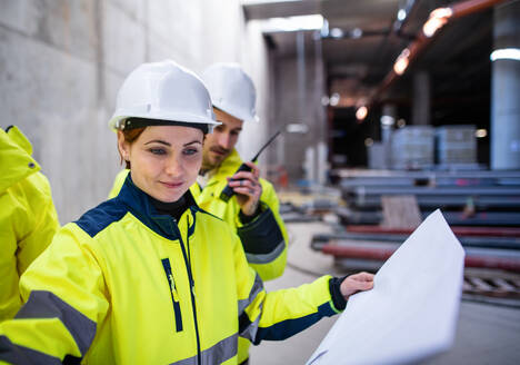 Eine Gruppe von männlichen und weiblichen Ingenieuren steht auf einer Baustelle und arbeitet. - HPIF15614