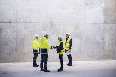 Eine Gruppe von Ingenieuren steht auf einer Baustelle und schüttelt sich die Hände. Kopierraum. - HPIF15619
