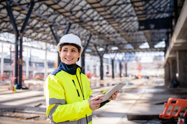 Eine Frau, die als Ingenieurin mit einem Tablet auf einer Baustelle steht und arbeitet. Raum kopieren. - HPIF15630