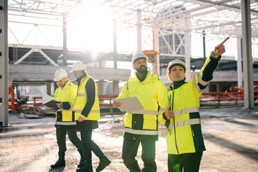 Eine Gruppe von Ingenieuren steht im Freien auf einer Baustelle und arbeitet. - HPIF15651