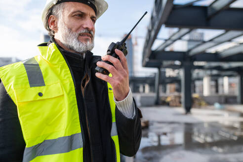 Man engineer using walkie talkie outdoors on construction site. - HPIF15654
