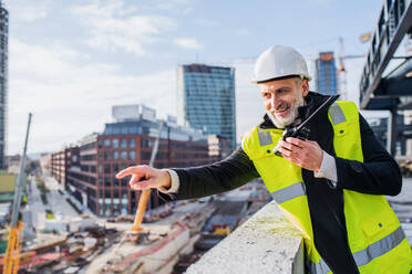 Man engineer using walkie talkie outdoors on construction site. - HPIF15655