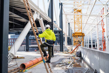 Rückansicht eines Mannes, der auf einer Baustelle im Freien arbeitet. - HPIF15661