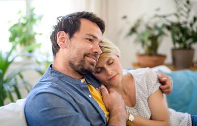 Vorderansicht eines verliebten, glücklichen Paares, das zu Hause sitzt und sich umarmt. - HPIF15716