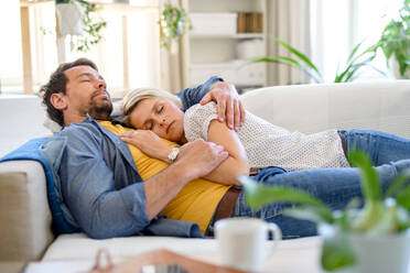 Happy couple in love lying on sofa indoors at home, sleeping. - HPIF15721