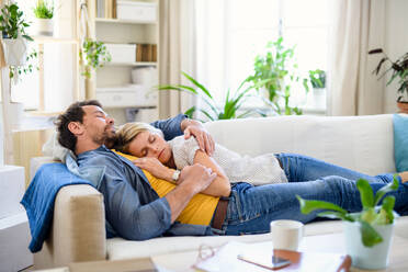 Happy couple in love lying on sofa indoors at home, sleeping. - HPIF15722