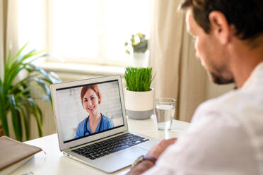 Reifer Mann, der ein Videogespräch mit einem Arzt am Laptop zu Hause führt, Konzept der Online-Konsultation. - HPIF15744